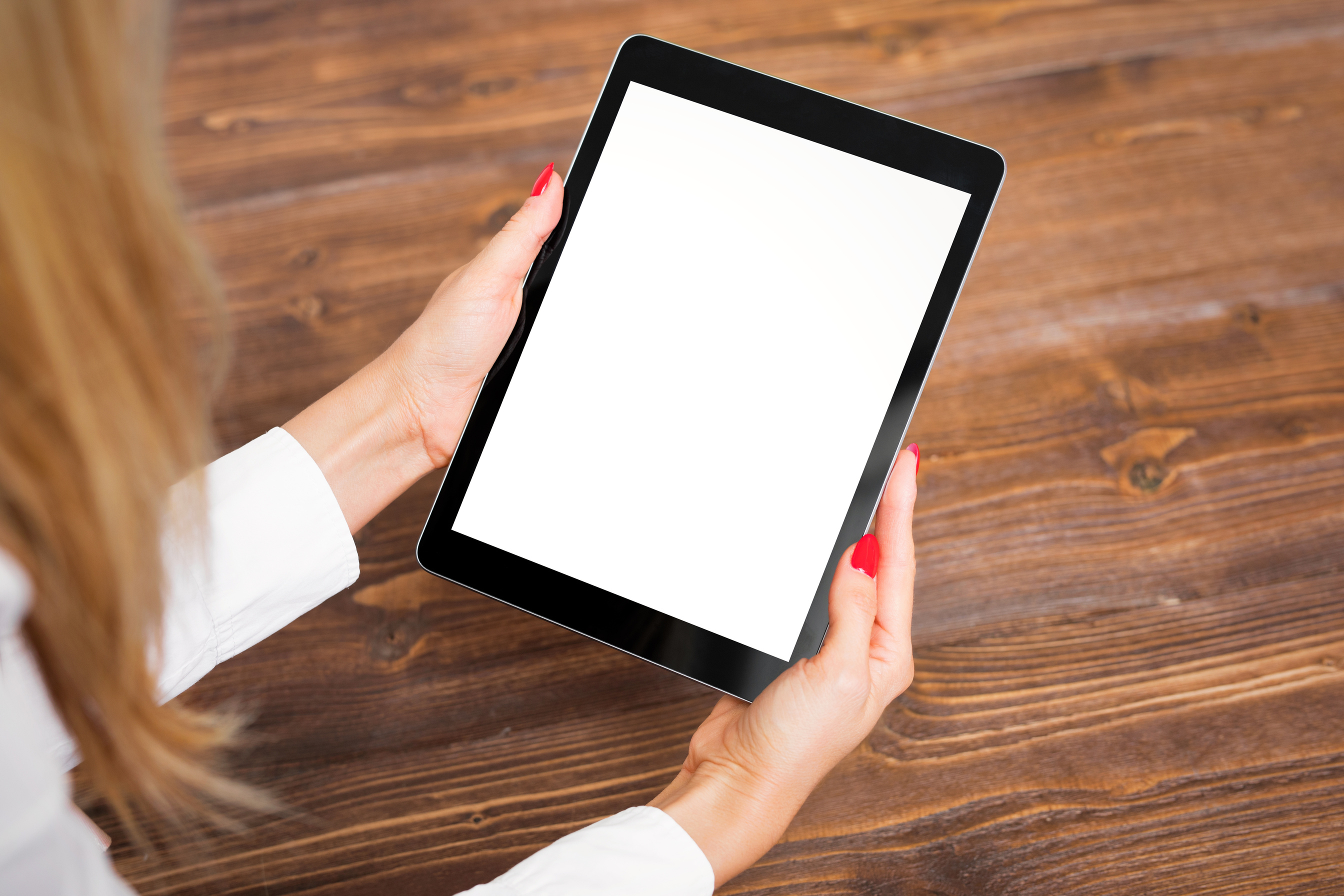 Woman Holding Tablet on Wooden Table